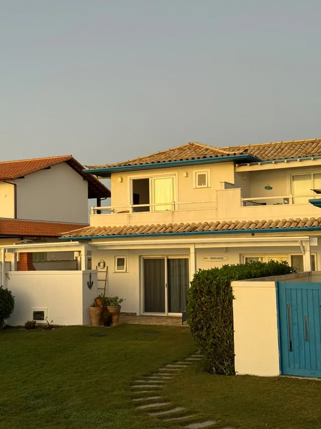 Fachada branca com janelas azuis e telhado de barro