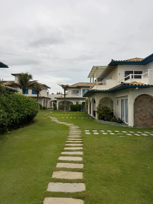 Caminho de pedras no gramado entre as casas brancas da pousada
