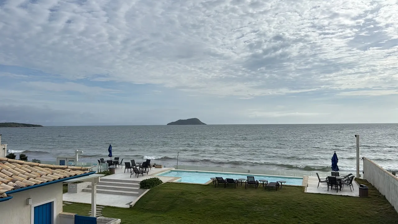 Piscina de borda no gramado com o mar e uma ilha ao fundo