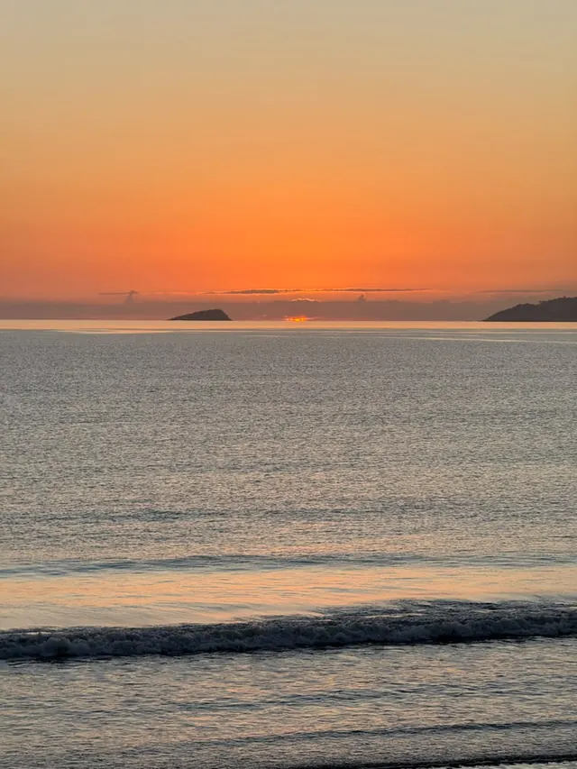 Céu laranja no fim de tarde com uma ilha no horizonte